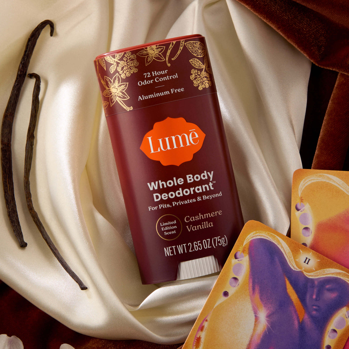 Lume Deodorant stick in the scent Cashmere Vanilla on top of luxe fabric and vanilla beans.