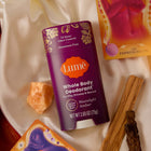 A stick of Lume Deodorant in the scent Moonlight Amber, overlaying crystals and tarot cards.
